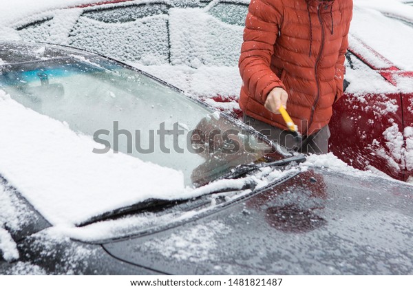 The guy cleans the car from the snow with a\
brush, Bad snow weather\
concept