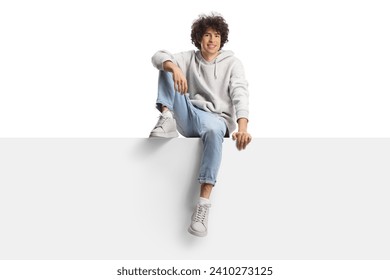 Guy with curly hair sitting on a panel and smiling isolated on white background
