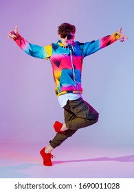Guy dancing contemporary dance in studio. Neon light grey background. Acrobatic bboy dancer. Break dance lessons.