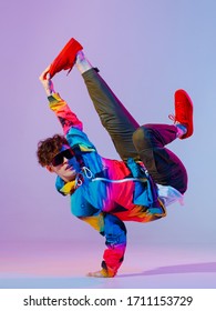 Guy Dancing Contemporary Dance In Studio. Neon Light Grey Background. Acrobatic Bboy Dancer. Break Dance Lessons.