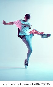 Guy dancing contemporary dance in studio. Neon light blue background. Acrobatic bboy dancer. Break dance lessons.