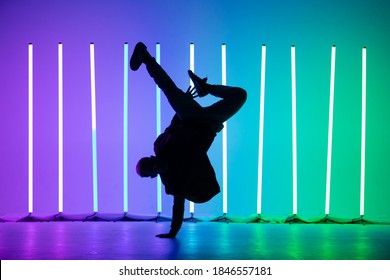 Guy dancing contemporary dance in studio. Neon light tube background. Acrobatic bboy dancer. Break dance lessons.
