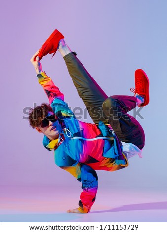 Guy dancing contemporary dance in studio. Neon light grey background. Acrobatic bboy dancer. Break dance lessons. ストックフォト © 