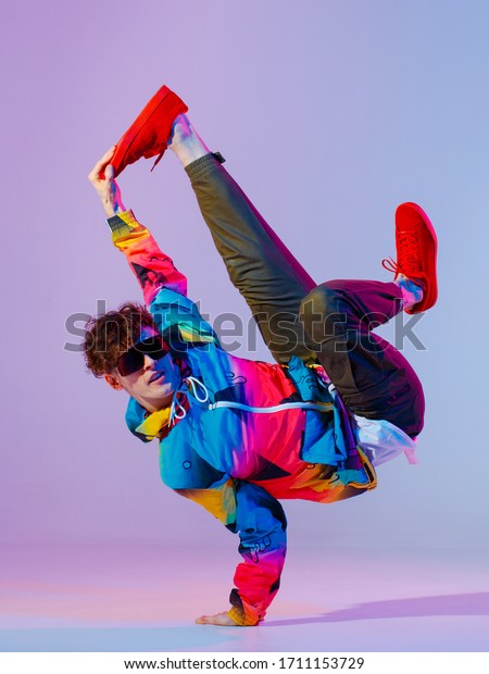 Guy dancing\
contemporary dance in studio. Neon light grey background. Acrobatic\
bboy dancer. Break dance\
lessons.