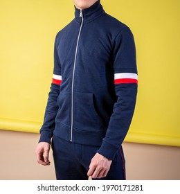 guy in a dark blue tracksuit on a yellow background