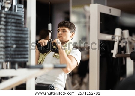 Guy does the exercise on the machine and pulls the handle vertically, training the muscles of the back and arms. Strength training of the back and biceps muscles using a narrow grip
