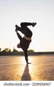 Guy doing parkour and breakdancing tricks at sunset in the street