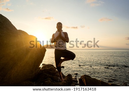 guy doing yoga poses on sharp rocks near the beach in Thailand
