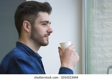 the guy is drinking tea and looking out the window