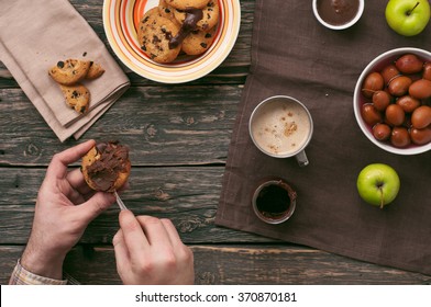 guy eating breakfast cookies with chocolate and cup of cappuccino on a wooden table. Top view with copy space