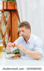 Guy Eats Grilled Chicken Wings And Drinks Beer In A Restaurant