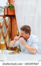 Guy Eats Grilled Chicken Wings And Drinks Beer In A Restaurant