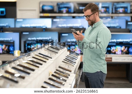 guy in an electronics store chooses a cell phone to buy.