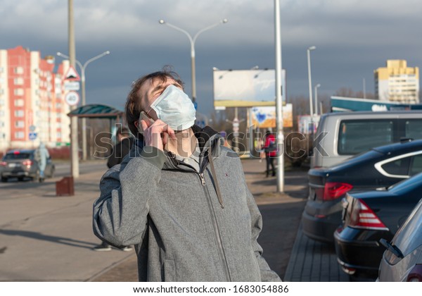 guy emotionally talking on a cell phone on the street.\
On the face a protective mask against coronavirus. Protection\
against bacteria and viruses transmitted by airborne droplets.\
passers-by around. 