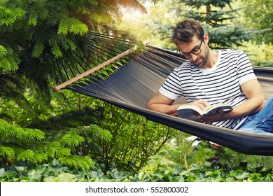 Guy Enjoying Lazy Afternoon On Hammock With Book