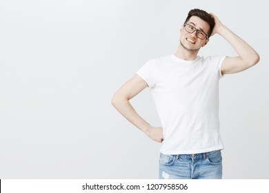 Guy feeling confused picking gift in cosmetics shop scratching back of head clueless making tight awkward and unsure smile tilting head and holding hand on waist being uncertain and questioned