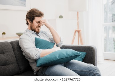 Guy feeling unwell with a stomach ache while sitting at home - Shutterstock ID 1627967725