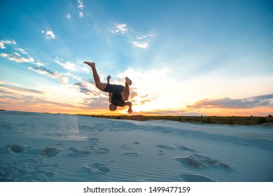 guy flies upside down on sand in the desert.