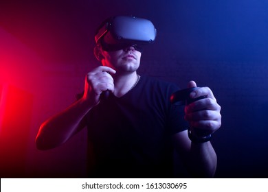 guy a gamer in modern wireless glasses of virtual reality plays a shooter, a man is focused on a 3D game in a dark room