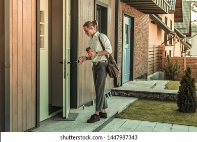 Guy Getting Ready. Rushing Stylish Guy In White Shirt Carrying Cup Of Coffee And Closing Door Of His House