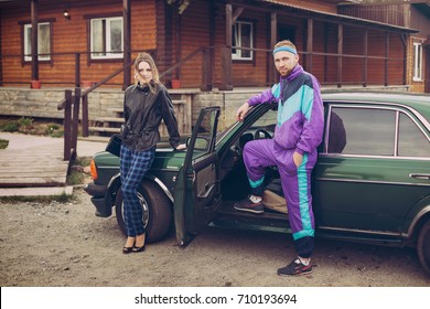 Guy And Girl In Clothes Of The Nineties, Next To The Old Car