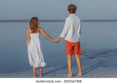 A guy and a girl hold hands and look into the distance