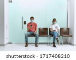 A guy and a girl in medical masks, sitting in a queue, and waiting for a doctor
