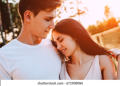 The guy and the girl with the perfect smile, laugh and look forward in the background of a Sunny day. Beautiful young couple during a romantic date. - Shutterstock ID 671908984