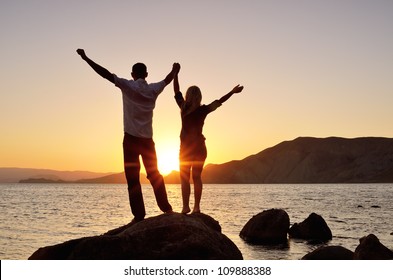 Guy with Girl raised her hands to the sky and watching the sun
