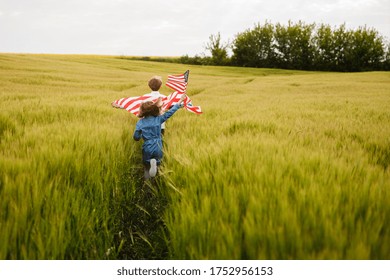 Guy and girl running in a field with an American flag in their hands. . Independence Day - Powered by Shutterstock