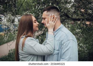 a guy and a girl stand against the background of a flowering tree and are going to kiss