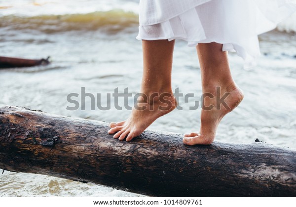 男と女の子は裸足で浜辺を歩き 女の子は波を揺らし 水しぶきを浴びせ 女の子ははだしできちんと歩く丸太の上を歩く の写真素材 今すぐ編集