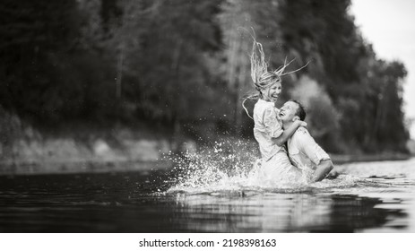 The Guy And The Girl Are Wet Kissing While Standing In The Water. Wet Clothes. Black And White Photography. Water Splashes Around.