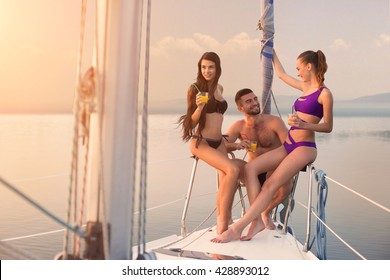 Guy With Girls On Yacht. People Sit On Yacht Railing. Summer Trip With Friends. What A Beautiful Day.