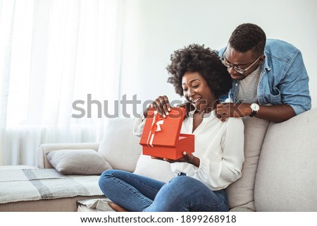 The guy gives a gift box to his girlfriend. Young couple on holiday. St. Valentine's Day. Smiling mid adult man surprising his girlfriend with a gift.  Couple celebrating Valentines day anniversary 