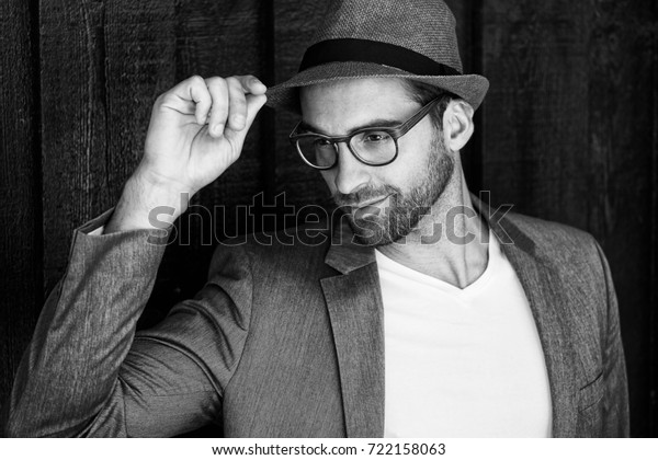 Guy\
in glasses and suit jacket tipping hat, looking\
away