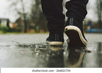 Guy goes in sneakers on the street in the rain