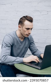 Guy in gray jacket, an IT specialist, sits at laptop and works - Shutterstock ID 2395070857