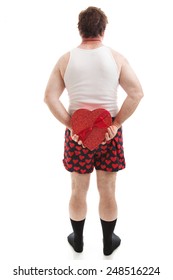 Guy In Heart Underwear Holding A Valentines Day Heart Shaped Box Of Candy Behind His Back.  Full Body On White.  