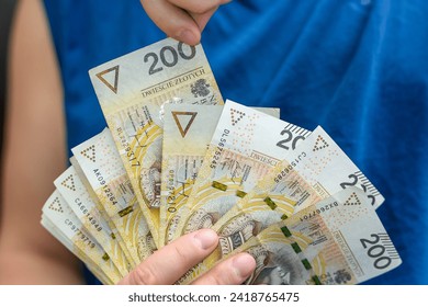 The guy is holding a fan of banknotes, Polish currency