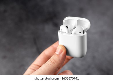 guy holds airpods case in hand. Air Pods. with Wireless Charging Case. New Airpods on 
scratch metal background. Airpods. EarPods