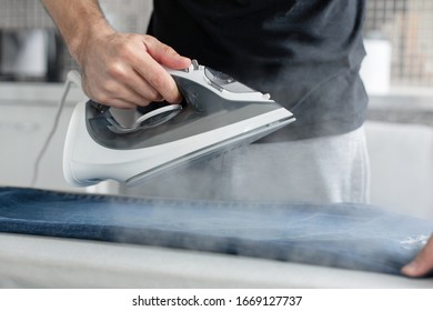 A Guy Ironing Clothes Before Going Outside.