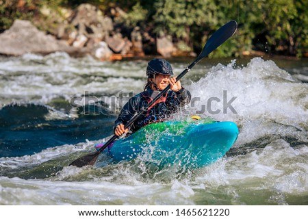 Guy in kayak sails mountain river. Whitewater kayaking, extreme sport rafting.