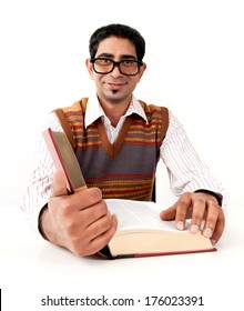 A guy with large glasses, is reading a large book.