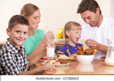 Guy is looking at the camera. His family has breakfast on background