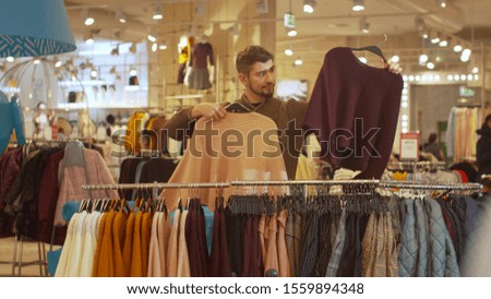 Guy is looking for a certain sweater in a store