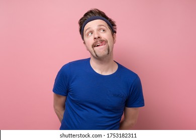 Guy Is Looking At Tasty Food After Sport Training Licking Lips Expressing Desire. Studio Shot On Pink Wall.