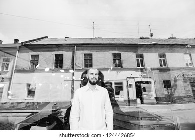 The guy is looking through the window and his photographer take pictures from the street. the window reflects the reflection of the photographer's silhouette