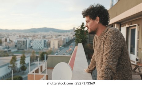 Guy looks at the city from the balcony, enjoys the beautiful view - Powered by Shutterstock