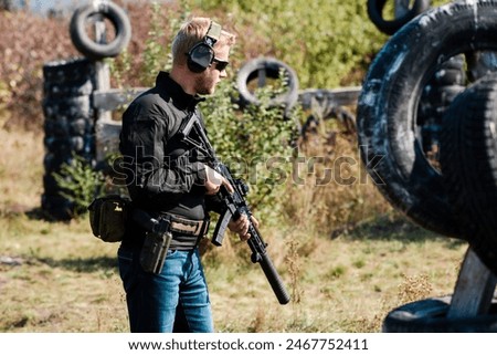A guy with a machine gun learns to shoot at a shooting range on a sunny day